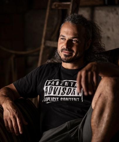 Mann im schwarzen T-Shirt sitzt entspannt in einer alten Scheune