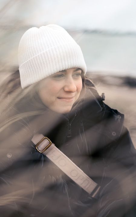 Junge Frau mit weisser Mütze am Strand, im Vordergrund unscharfe Formen