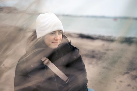 Junge Frau mit weisser Mütze am Strand, im Vordergrund unscharfe Formen