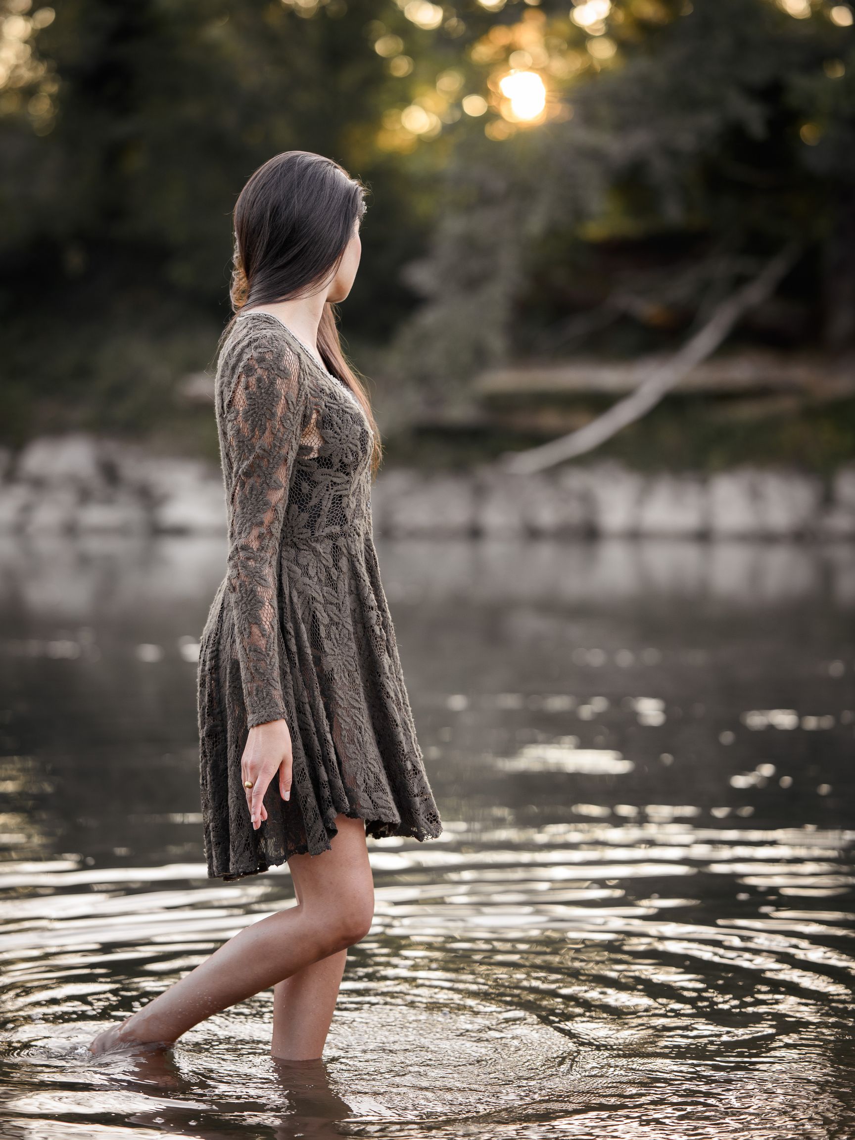 Frau im geblümten Sommerkleid mit Strohhut geht durch ein blühendes Lavendelfeld