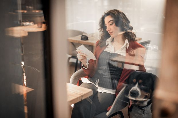 Frau mit Hund in einem Café, aufgenommen durch die Fensterscheibe