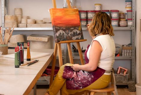 Frau malt in einem Atelier an einer Staffelei