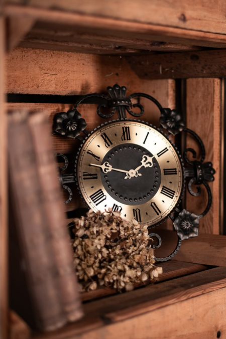 Antike Uhr und getrocknete Blüten in einer alten Holzkiste