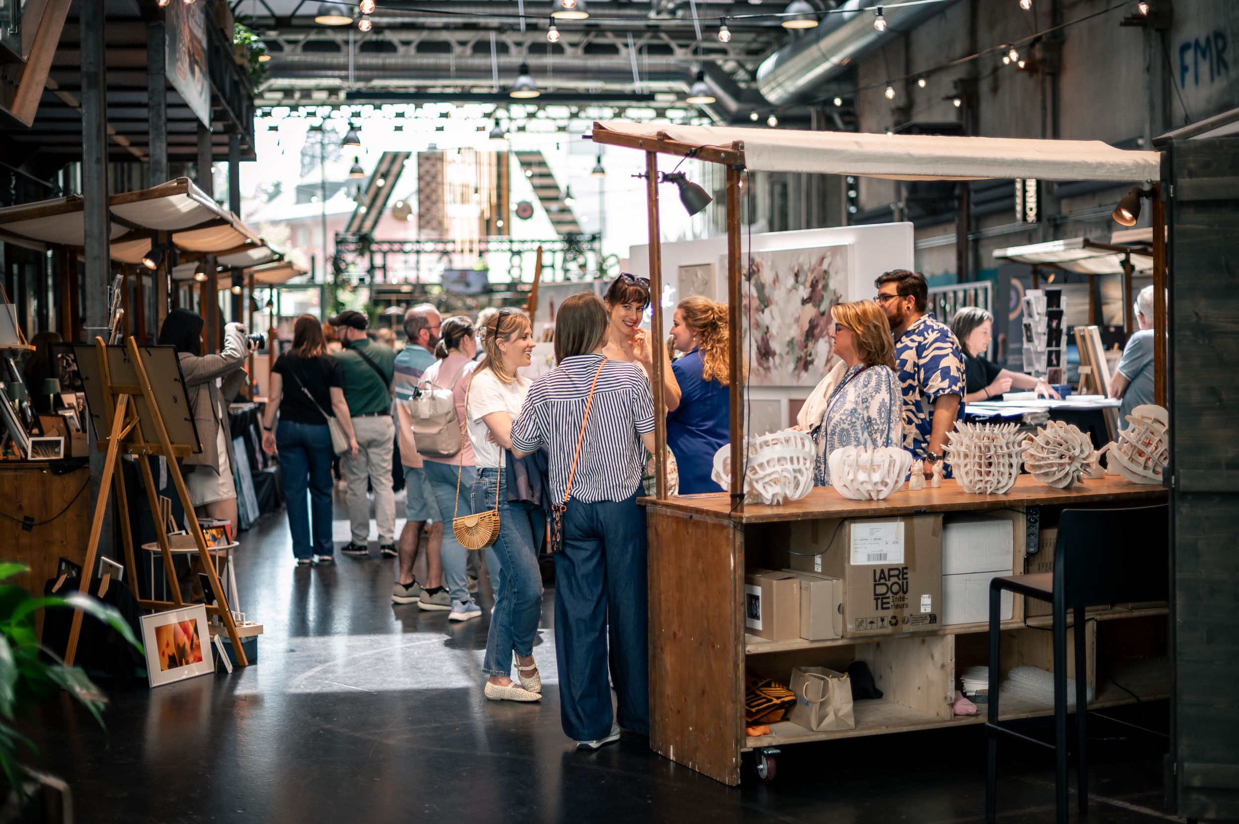 Gang durch eine Markthalle, Besucherinnen und Besucher zwischen den Ständen