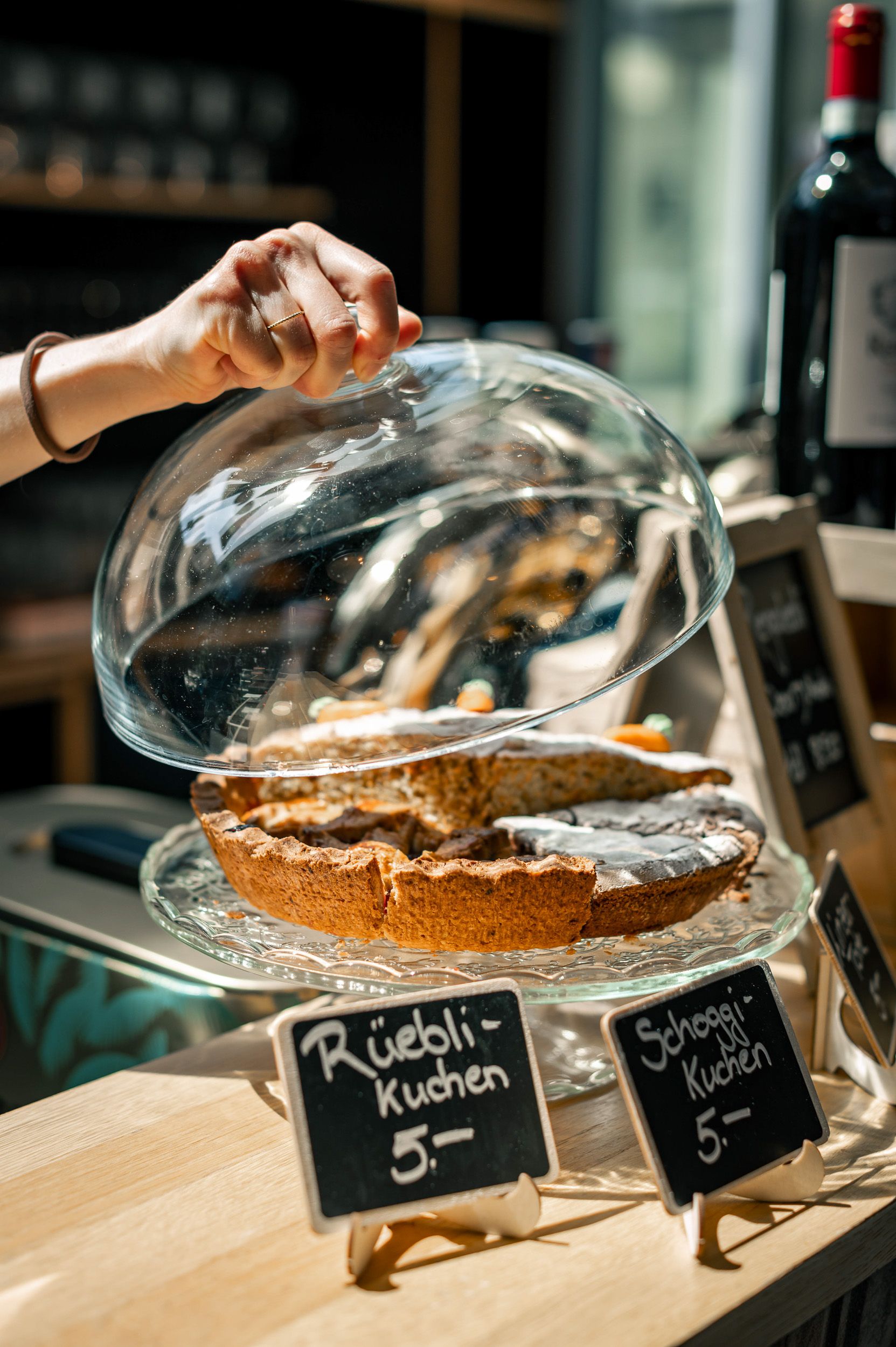 Kuchen unter einer Glasglocke, daneben ein beschriftetes Schild