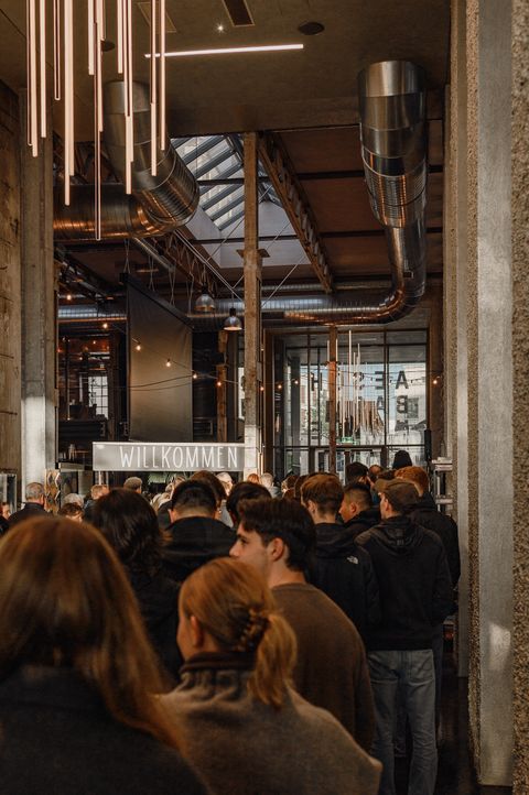Publikum in einer Industriehalle, Blick über die Köpfe Richtung Bühne