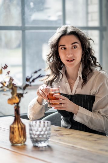 Simona mit einem Glas Tee an einem Fenstertisch