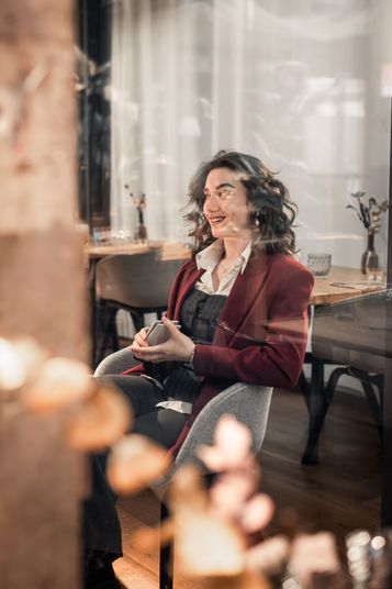Simona sitzt in einem Café, im Vordergrund unscharfe Lichter