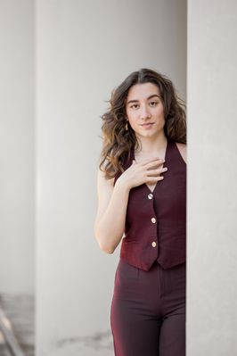 Simona in weinroter Weste steht in einem hellen Durchgang