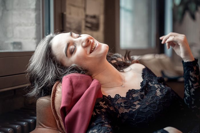 Simona liegt zurückgelehnt auf einem Sofa und lacht