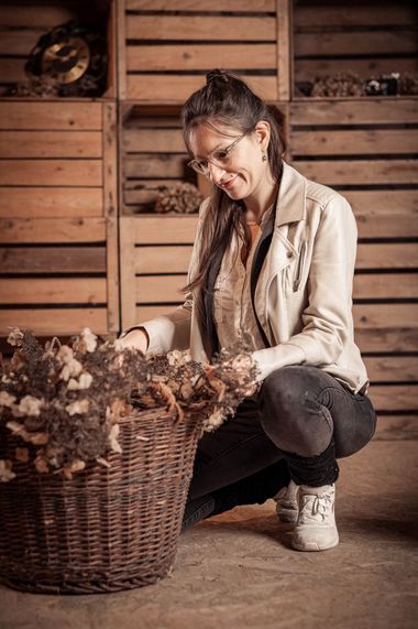 Seraina Wild kniet vor Holzkisten und ordnet getrocknete Hortensien in einem Korb