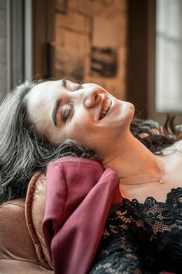 Frau liegt zurückgelehnt auf einem Sofa und lacht mit geschlossenen Augen
